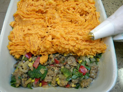 Piping on the mashed potato-squash topping.