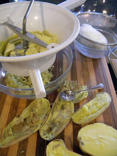 potatoes being placed in food mill in foreground and ricotta draining in background