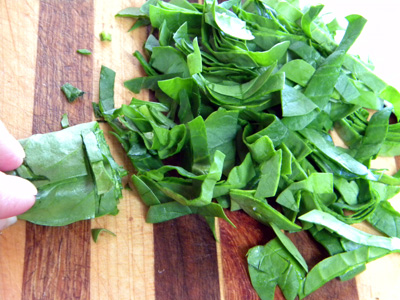 To slice leafy greens and herbs such as the spinach and basil, stack the leaves and roll, then thinly slice... this is a chiffonade.